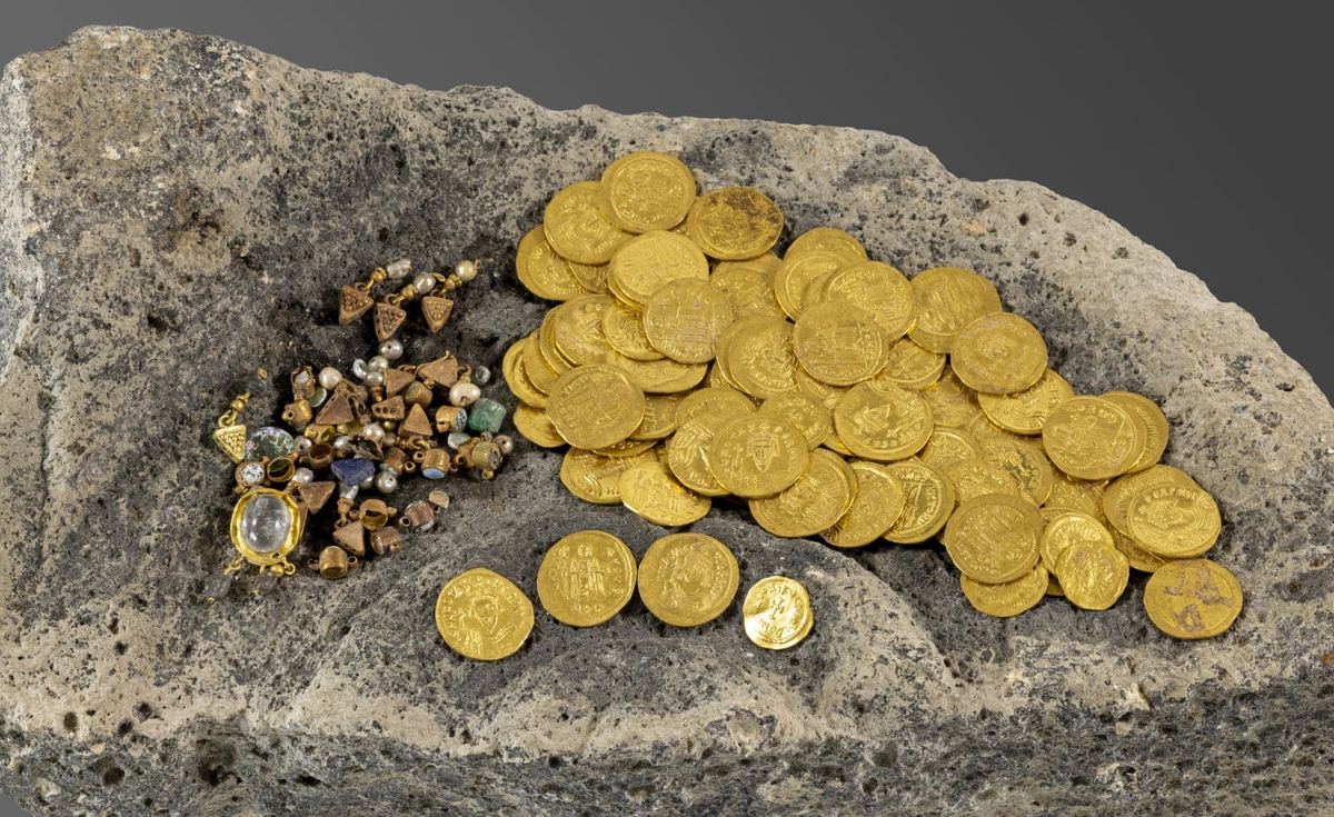 A pile of Byzantine gold coins and jeweled earrings resting on a block of stone