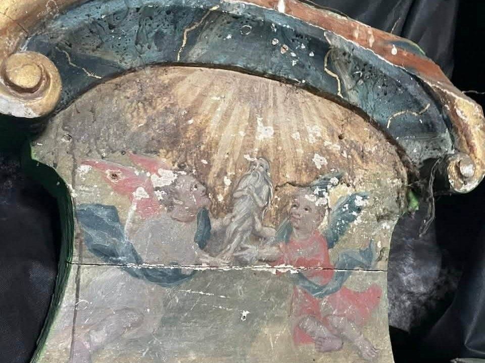 A worn, curved panel painted with golden rays and St. Onuphrius borne up by two angels