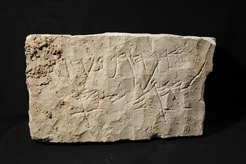 A pale limestone block with one line of Paleo-Hebrew letters cut across its face